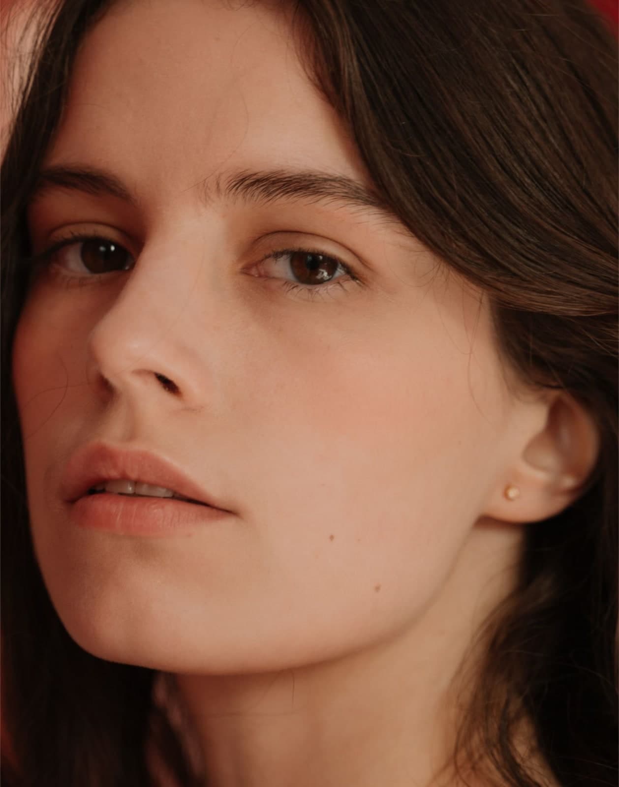 lose-up portrait of a person with mostly clear skin and a few small red blemishes on the chin and lower face, illustrating mild inflammatory acne.